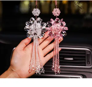 Detailed view of pink and clear crystal flower car hanging ornaments held by hand
