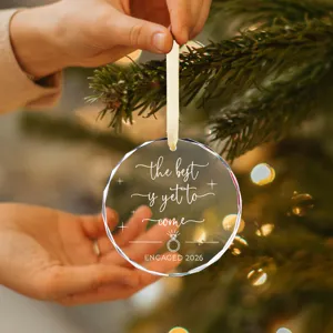 Close-up van gegraveerde glazen kerstversiering met tekst voor verloving in 2026