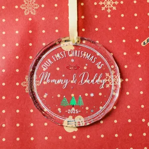 Detailopname van Mommy & Daddy 2025 kerstornament van acryl op een rode feestelijke basis