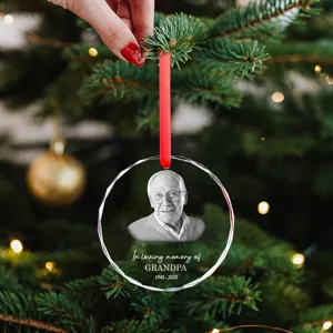 Detalle de un adorno navideño conmemorativo de cristal con la foto de un abuelo.