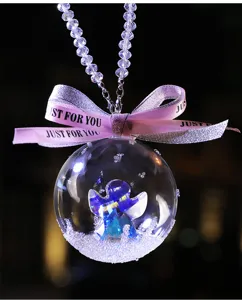 Close-up of a crystal ball car hanging ornament with a blue iridescent angel and pink ribbon