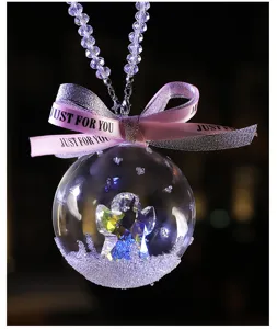Close-up of crystal ball car pendant featuring a faceted angel and pink bow ribbon