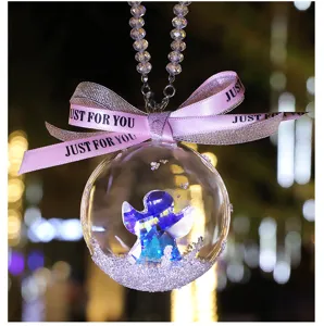 Close-up detail of a crystal ball car hanging with a blue angel and JUST FOR YOU pink ribbon.