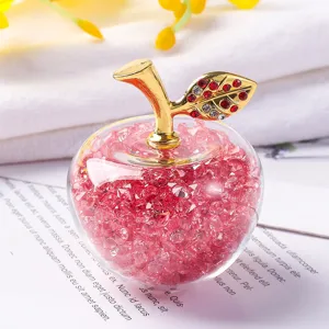 Gros plan d'une pomme décorative en cristal remplie de gravier rouge et tige dorée