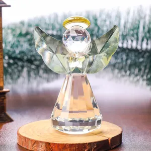 Primer plano de una figurita de ángel de cristal minimalista con aureola dorada sobre madera