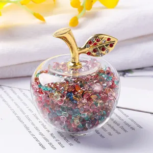 Gros plan d'une pomme en cristal remplie de strass colorés et feuille dorée.