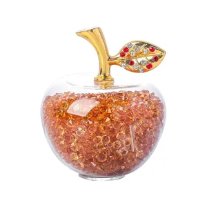 Vue détaillée d'un ornement de pomme en cristal rempli de pierres ambrées et d'une feuille d'or
