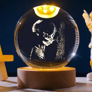Detail van een kristallen bol nachtlamp met 3D-foetus echografie gravure op houten basis