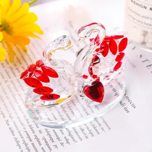 Detailed close-up of elegant crystal swan couple with red gemstone wings on base