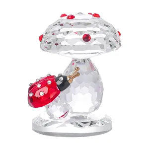 Dettaglio macro di una statuina di fungo in cristallo sfaccettato con una piccola coccinella.