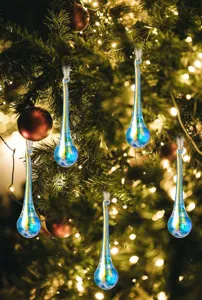 Primer plano de elegantes adornos navideños en forma de gota irisada con luces cálidas
