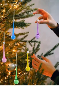 Adornos de lágrima de cristal de colores colgados en un árbol de Navidad iluminado