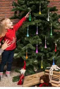 Vibrantes adornos navideños en forma de lágrima de colores colgados en un árbol de Navidad