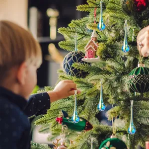 Elegantes adornos de cristal azul y amarillo en forma de lágrima en un árbol de Navidad