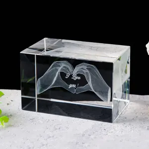 Detalle del grabado láser 3D de manos formando un corazón dentro de un bloque de cristal