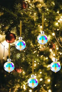 Faceted iridescent crystal ball ornaments hanging on a decorated Christmas tree