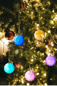 Macro view of multi-colored 30mm round faceted crystal prisms hanging on a Christmas tree.