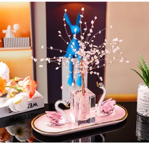 Elegant detail shot of pink K9 crystal swan ornaments and life tree on a decorative pink tray.