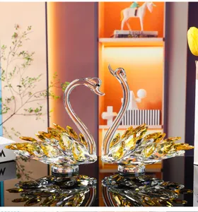 Close-up of elegant crystal swan pair figurines with amber facets on reflective surface