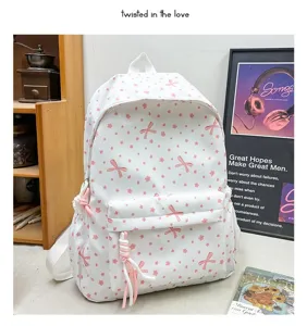 Vista detallada de mochila blanca con lazos rosas en un ambiente acogedor de dormitorio