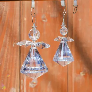 Primer plano de atrapasoles ángeles de cristal tallado colgados sobre fondo madera
