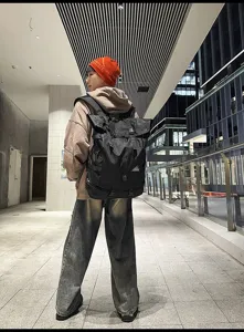 Detailansicht eines großen schwarzen Roll-Top-Sportrucksacks, getragen von einem Modell