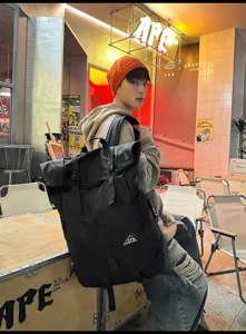 Seitenansicht eines großen schwarzen Roll-Top-Sportrucksacks, getragen von einem Modell