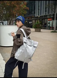 Großer lichtgrauer Roll-Top Outdoor-Rucksack, getragen von einem Modell im urbanen Raum