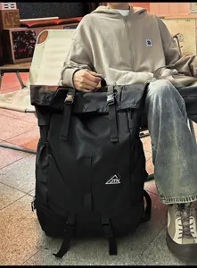 Großer schwarzer Roll-Top-Sportrucksack mit Schnallenriemen in einer Lifestyle-Umgebung