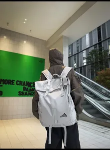 Rückansicht eines grauen Sportrucksacks mit Rollverschluss, getragen von einer Person im Freien