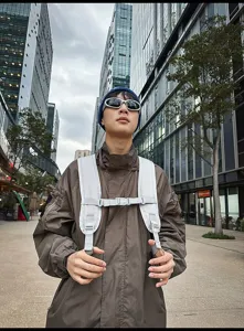 Detailansicht der grauen Sportrucksack-Gurte und Brustschnalle an einem Modell in der Stadt.