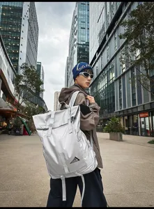 Großer silberner Roll-Top Reise-Rucksack mit Schuhfach, getragen von einem Modell im Freien
