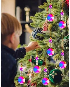 Detailansicht eines Kindes das bunte Kristallprismen an einen festlichen Weihnachtsbaum hängt