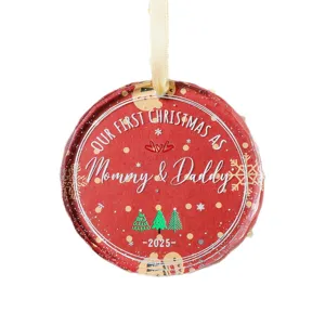 Rood rond kerstornament met de tekst 'Our First Christmas as Mommy & Daddy 2025'.