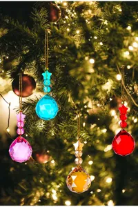 Detail van kleurrijke kristallen bolornamenten die aan een verlichte kerstboom hangen