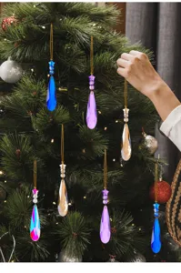 Gekleurde kristallen kerstboomhangers in druppelvorm aan een groene kerstboom tak