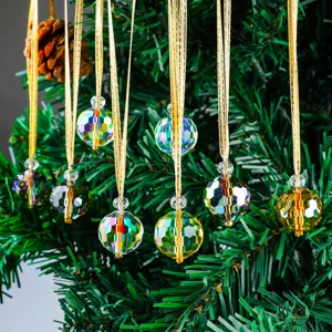 Sparkling multifaceted crystal Christmas tree ornaments with golden ribbons hanging on branches