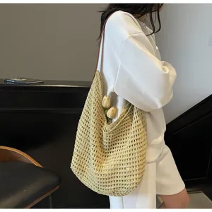 Detailed side view of a large yellow bohemian knitted mesh tote bag worn by a model