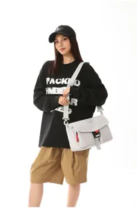 Modelo con bolso bandolera utilitario gris claro y camiseta negra de manga larga