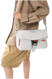 Primer plano de un bolso bandolera funcional gris llevado por un modelo en estudio fotográfico.
