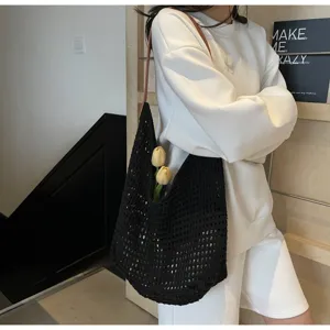 Detail of black crochet mesh tote bag styled with yellow tulips on a model.