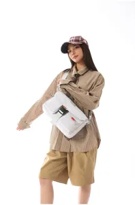 Bolso bandolera funcional techwear gris claro con correas ajustables en una modelo.