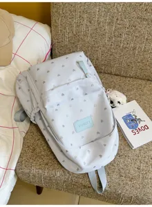 Detailed view of casual white backpack featuring silver heart pattern and brand label