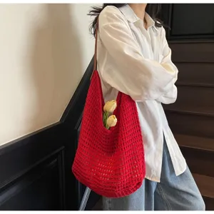 Vibrant red hollow-out knitted mesh shoulder bag carried by a model in a chic indoor setting