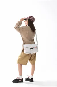 Modelo con un bolso mensajero blanco funcional en un estilo minimalista de moda urbana