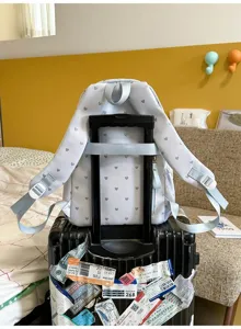 Back view of heart pattern backpack showing luggage strap on suitcase handle