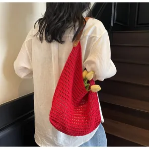 Detailed view of red hollow-out knitted mesh bag with brown leather strap
