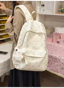 Detailed side view of off-white backpack featuring grey heart patterns and a cute plush charm