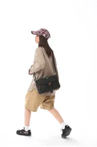 Vista lateral de un bolso bandolera funcional negro de estilo cargo en un modelo