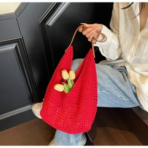 Close-up detail of a bright red hollow-out crochet knit hobo bag with yellow tulips